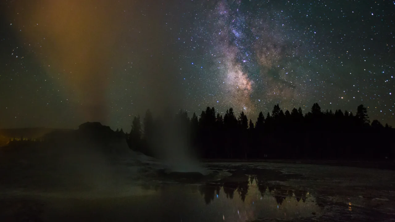 Steaming geysers beneath a star-filled sky in Yellowstone National Park